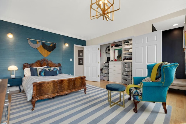 bedroom with ornamental molding, a closet, wood finished floors, and a notable chandelier