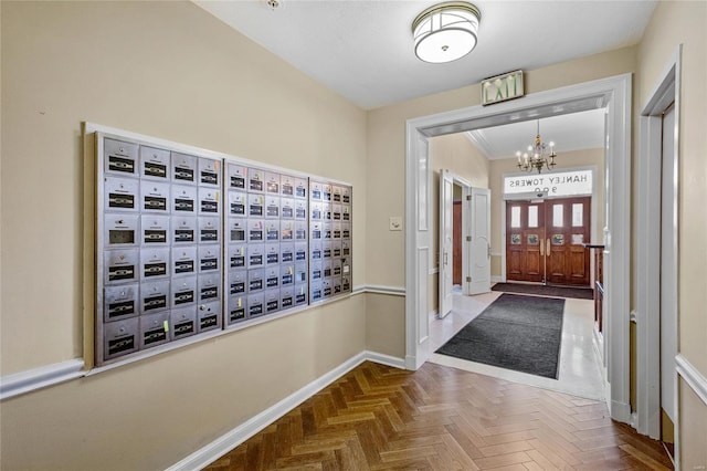 foyer featuring baseboards, mail area, and a chandelier
