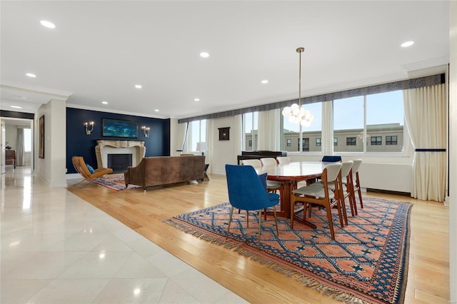 dining area featuring light tile patterned flooring, an inviting chandelier, a fireplace, baseboards, and ornamental molding