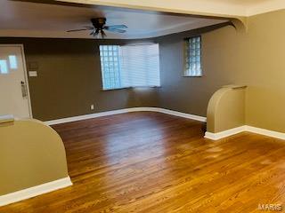 empty room with baseboards, a ceiling fan, and wood finished floors
