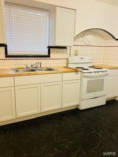 kitchen featuring white cabinets, a sink, decorative backsplash, electric range, and custom range hood