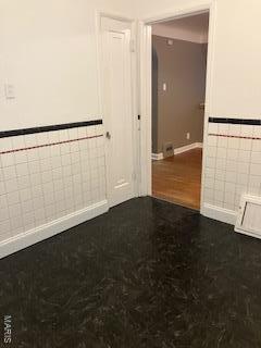 spare room featuring tile walls and wainscoting