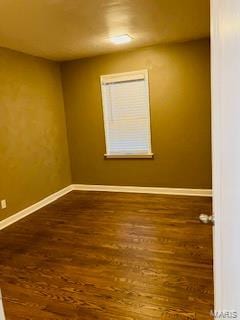 empty room featuring dark wood finished floors and baseboards