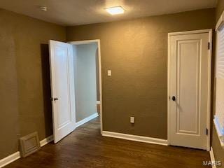 unfurnished room with baseboards, wood finished floors, and visible vents