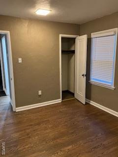 unfurnished bedroom featuring baseboards, a closet, and dark wood finished floors