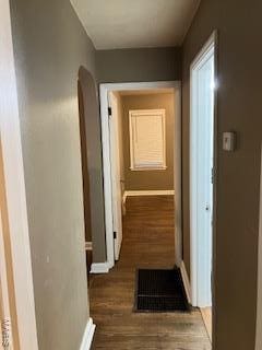 hallway with visible vents, wood finished floors, baseboards, and arched walkways