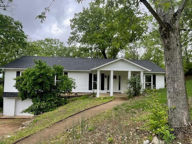 view of front of property featuring an attached garage, roof with shingles, covered porch, and driveway