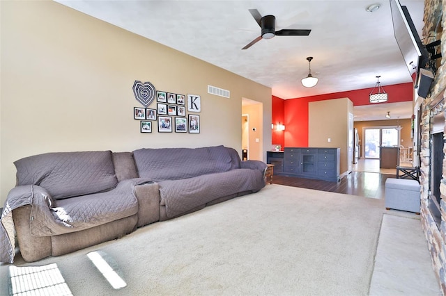 living room with visible vents, wood finished floors, ceiling fan, and carpet floors