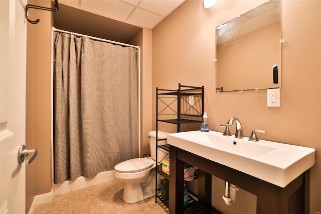 bathroom featuring a shower with shower curtain, toilet, tile patterned flooring, and a drop ceiling