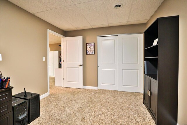 interior space with baseboards, light carpet, a closet, and a drop ceiling