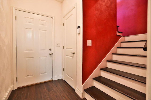 foyer featuring dark wood-style flooring, stairway, and baseboards