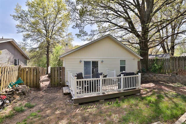 back of house featuring a chimney, a wooden deck, and a fenced backyard