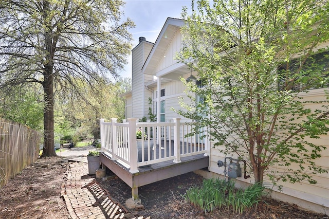 view of side of property with fence, a chimney, and a deck