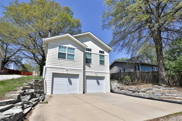 exterior space with concrete driveway, an attached garage, board and batten siding, and fence