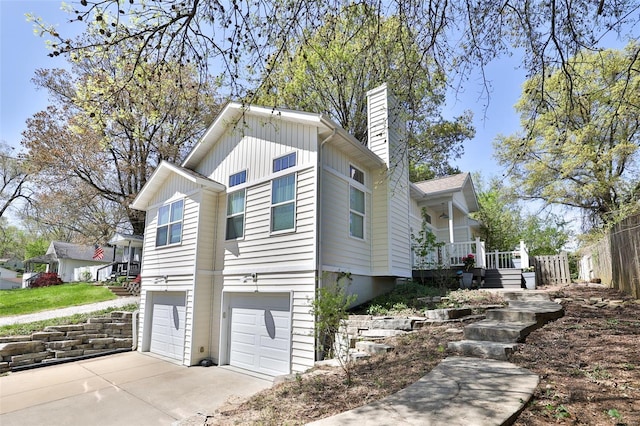 view of property exterior with a chimney, board and batten siding, covered porch, driveway, and an attached garage