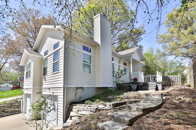 view of side of home featuring an attached garage, board and batten siding, and a chimney