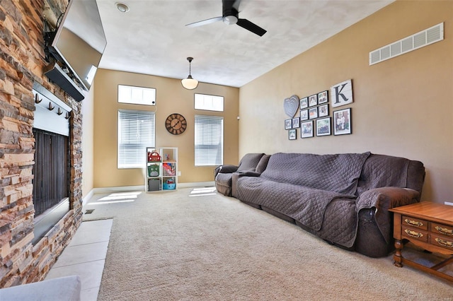 carpeted living area featuring a fireplace, visible vents, a ceiling fan, and baseboards