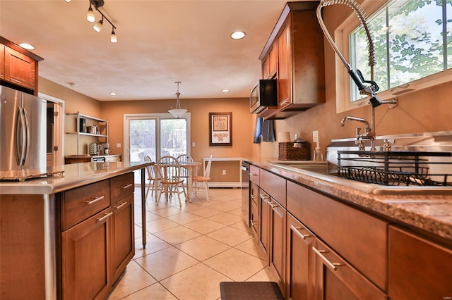 kitchen featuring light tile patterned floors, brown cabinets, appliances with stainless steel finishes, recessed lighting, and hanging light fixtures