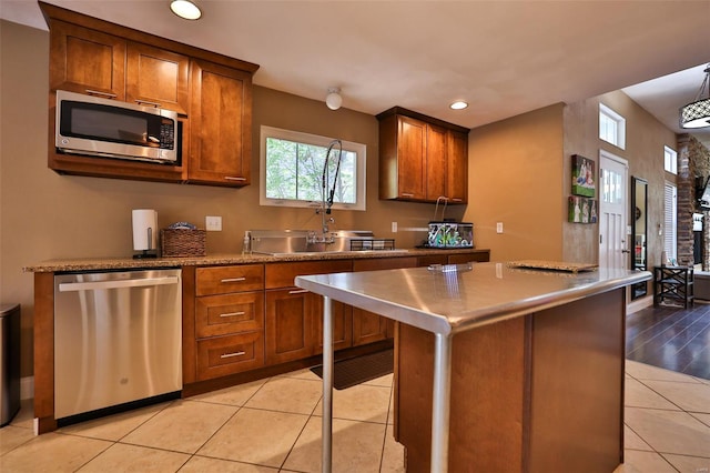 kitchen featuring a sink, brown cabinets, light tile patterned floors, and stainless steel appliances