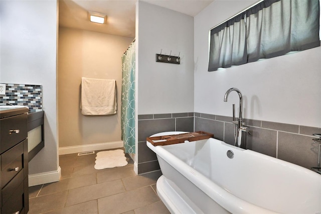 bathroom featuring baseboards, a freestanding tub, tile patterned flooring, and vanity