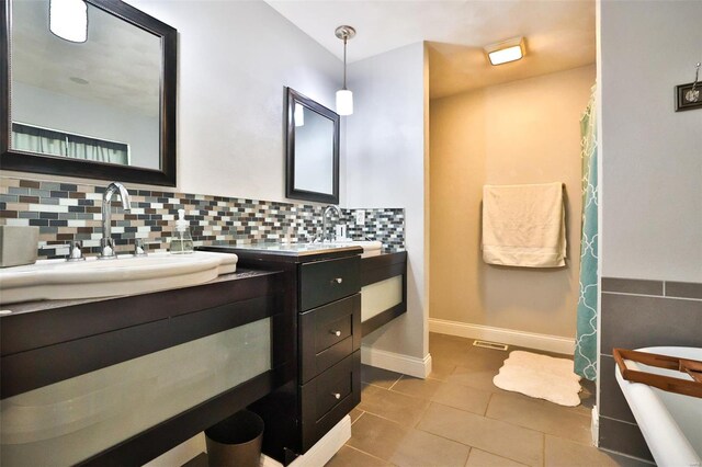 full bath featuring vanity, tasteful backsplash, tile patterned flooring, and baseboards