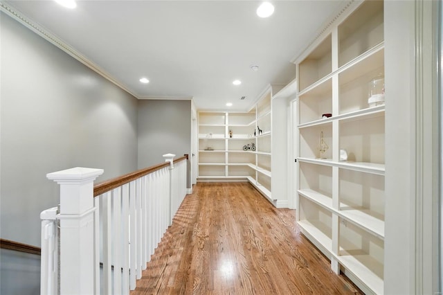 interior space featuring recessed lighting, an upstairs landing, built in shelves, wood finished floors, and ornamental molding