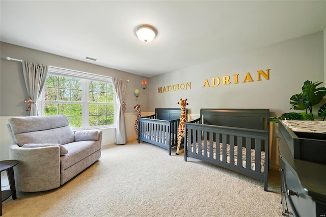 bedroom with visible vents, carpet floors, and a nursery area
