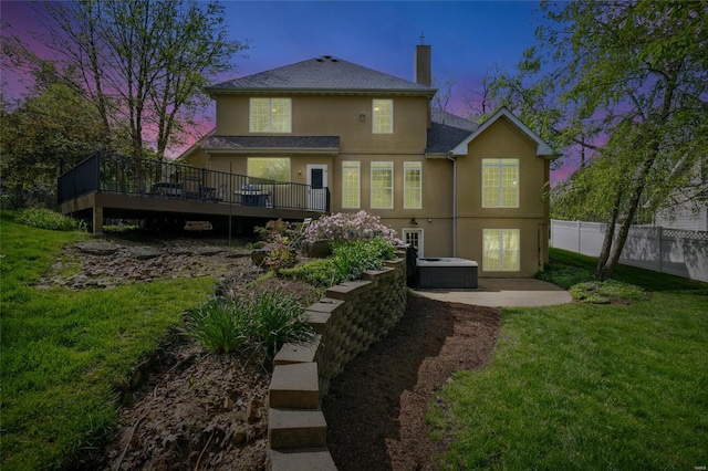 back of property featuring a chimney, fence, a yard, stucco siding, and a wooden deck