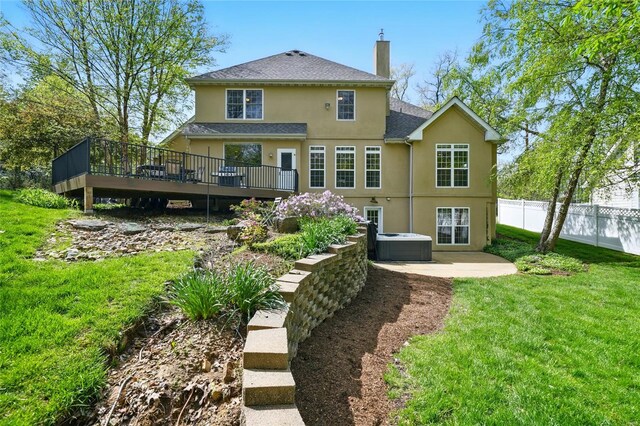 rear view of house featuring a chimney, fence, stucco siding, a lawn, and a deck
