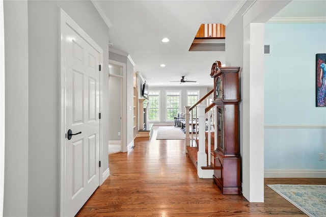 corridor featuring recessed lighting, wood finished floors, baseboards, and ornamental molding