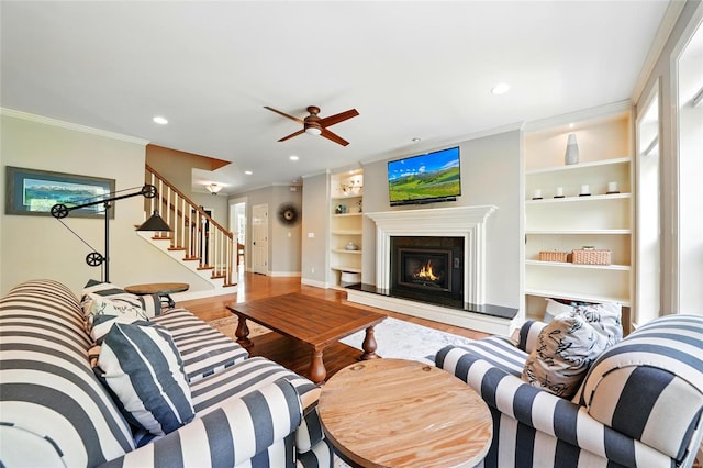 living area with wood finished floors, built in features, baseboards, and stairway