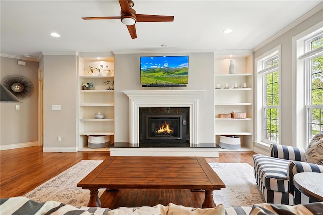 living room featuring built in shelves, ornamental molding, wood finished floors, and a premium fireplace