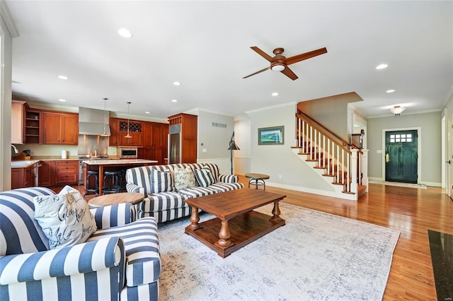 living room with stairway, light wood-style floors, ornamental molding, visible vents, and recessed lighting