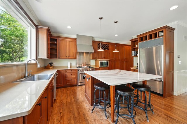 kitchen with open shelves, wall chimney range hood, built in appliances, and a sink
