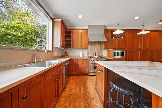 kitchen with wall chimney range hood, a sink, a breakfast bar, light wood-type flooring, and stainless steel appliances