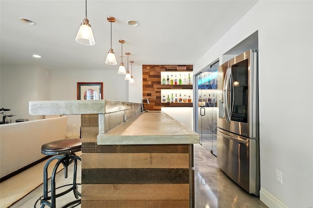 bar featuring recessed lighting, wet bar, a sink, decorative light fixtures, and stainless steel refrigerator with ice dispenser