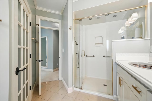 bathroom with a shower stall, crown molding, vanity, baseboards, and tile patterned flooring