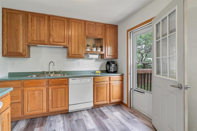 kitchen featuring brown cabinetry, white dishwasher, a sink, and light wood-type flooring