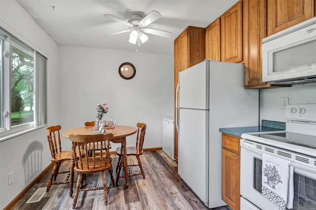 kitchen featuring white appliances, brown cabinetry, a ceiling fan, wood finished floors, and visible vents