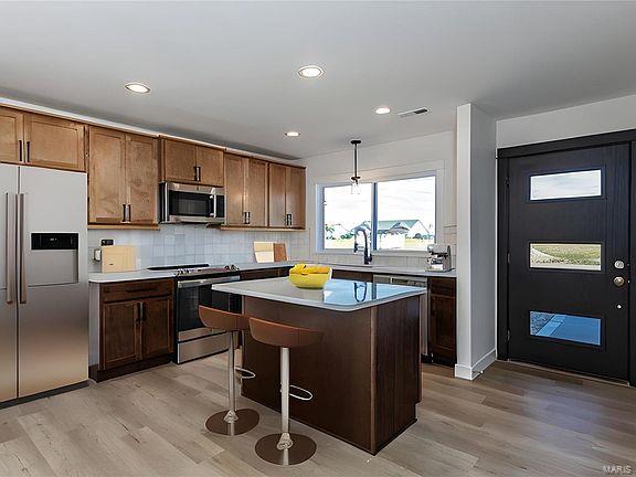 kitchen featuring tasteful backsplash, light wood-style flooring, appliances with stainless steel finishes, a kitchen island, and a sink