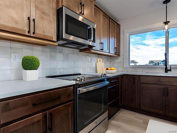 kitchen with a sink, light wood-type flooring, backsplash, light countertops, and appliances with stainless steel finishes