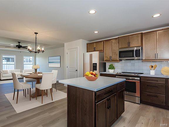 kitchen featuring light wood-type flooring, stainless steel appliances, backsplash, and light countertops