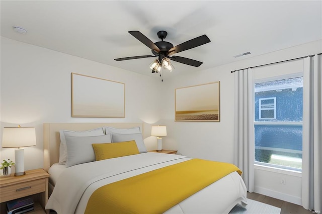 bedroom featuring a ceiling fan, visible vents, wood finished floors, and baseboards