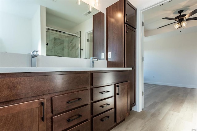 full bathroom featuring wood finished floors, ceiling fan, vanity, visible vents, and a stall shower