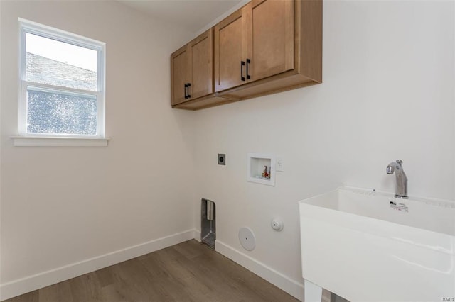 laundry room with a sink, cabinet space, hookup for a gas dryer, baseboards, and wood finished floors