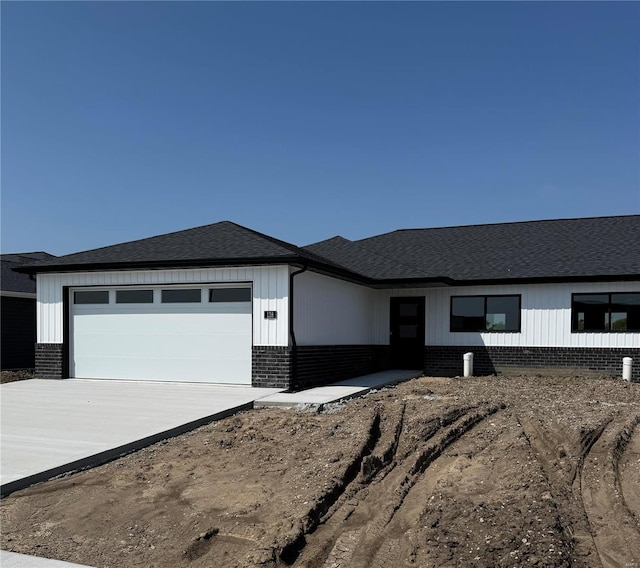 view of front of home with concrete driveway, a shingled roof, an attached garage, and brick siding