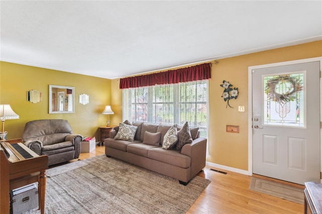 living area with light wood finished floors, visible vents, baseboards, and a healthy amount of sunlight
