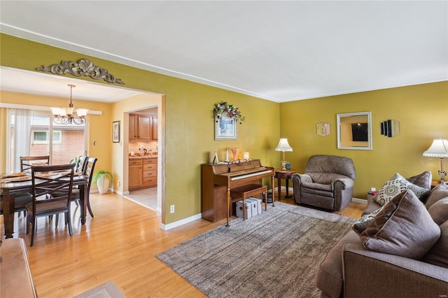 living area featuring a chandelier, baseboards, and light wood finished floors