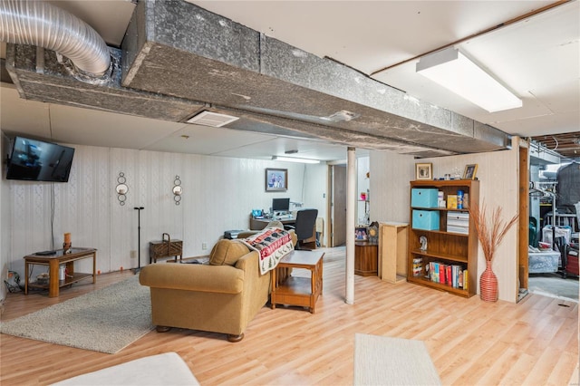 living area featuring wooden walls, wood finished floors, and visible vents