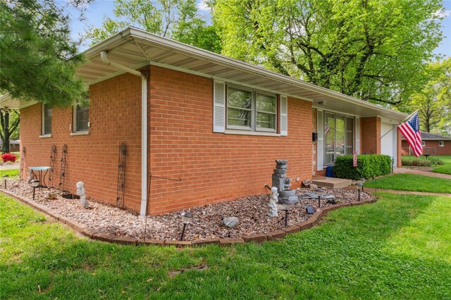view of home's exterior with a lawn, a garage, and brick siding